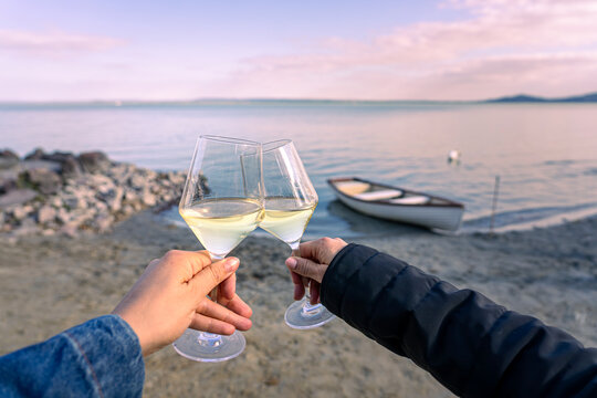 Couple toasting white wine at sunset by Lake Balaton, Hungary