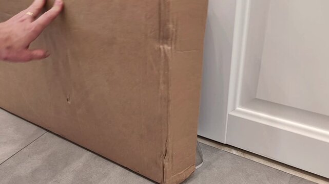 Female hand tries to close a cardboard furniture box, but the box springs open and a cardboard flap falls, unpacking and packing difficulty, horizontal video.