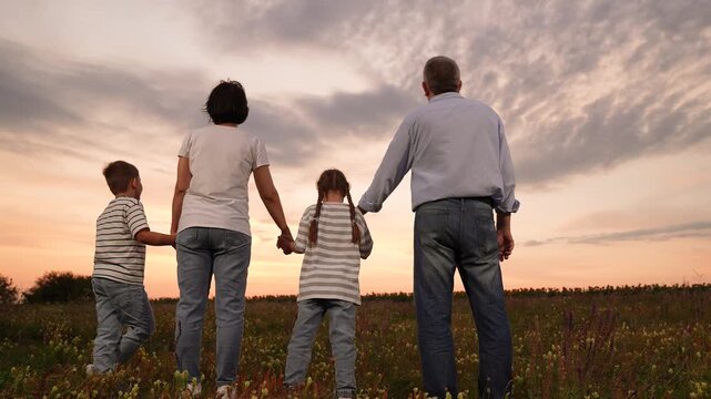 mother father children boy girl park sunset, man woman toddlers outdoors, Family walking in a field at sunset, parents and children holding hands, peaceful evening outdoors, unity and love, people