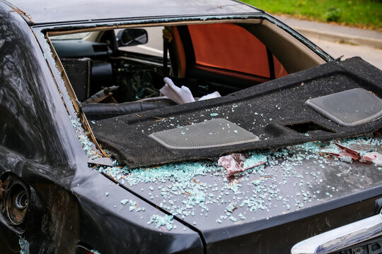 Broken rear car window with shattered glass fragments covering trunk and damaged window frame. Automotive glass replacement, vehicle repair and window restoration concept.