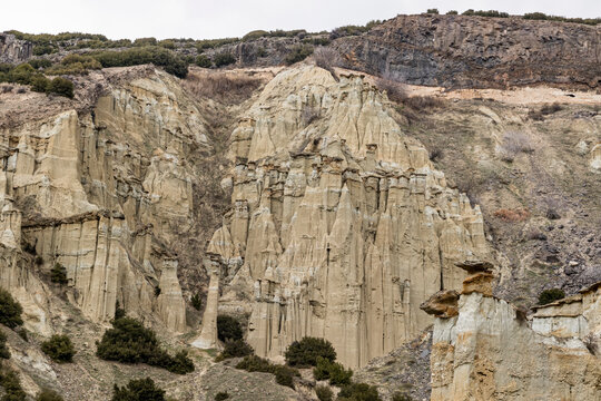 Scenic view of tall fairy chimneys and eroded volcanic rock formations against a mountain ridge