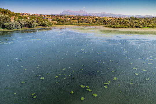 Bovansko Lake with lily pads surrounded by wetland vegetation, village, and Rtanj mountain range backdrop - Balkans.