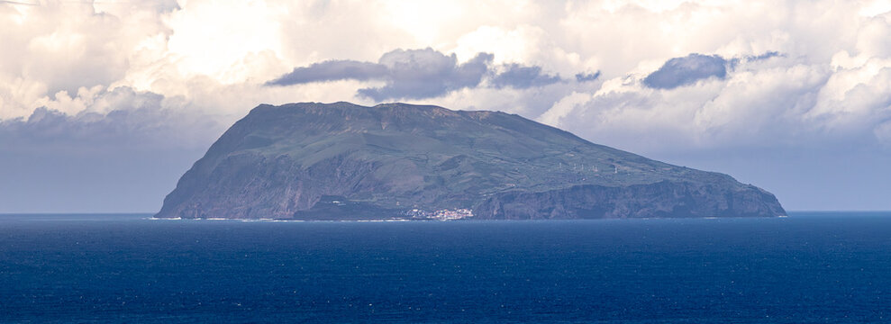 Silueta distante de la Isla de Corvo en el oc&eacute;ano Atl&aacute;ntico bajo un cielo tormentoso
