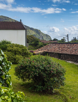 Jard&iacute;n rural y arquitectura tradicional azoriana con colinas de fondo en la Isla de Flores