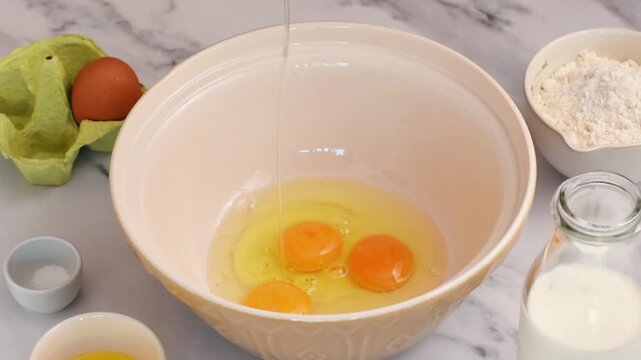 Woman's hands cracking an egg into a bowl with two eggs already cracked