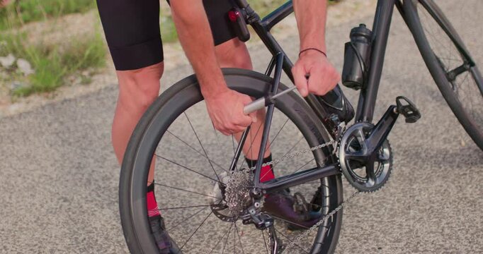 How to change a flat tire on a road bike while on a ride in the mountains near a winding asphalt road during the day
