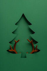 Merry Christmas and Happy New Year paper cut tree with reindeer antlers minimalist vertical green holiday design © ActionGP