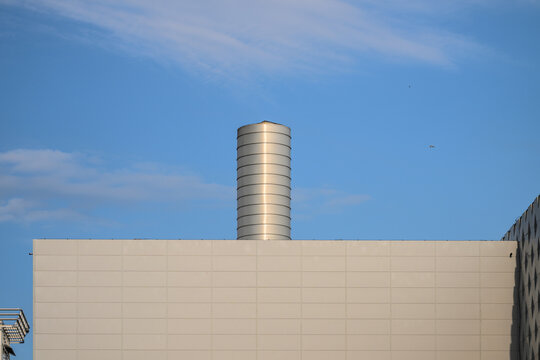 Cylindrical rooftop ventilation stack above modern industrial building.