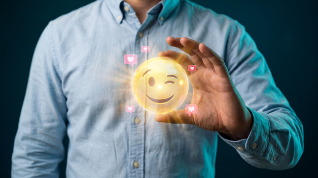 Businessman holding a glowing holographic winking smiley face with pink heart speech bubbles, representing customer satisfaction, positive feedback, service quality, and happy experience.