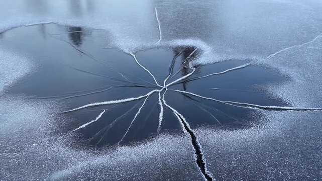 Frost cracking across a frozen puddle