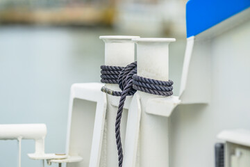 Marine mooring rope tied securely around white bollards. © Trygve