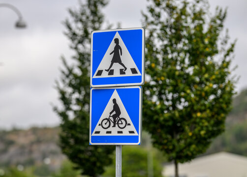 Swedish pedestrian and bicycle crossing signs beside urban road.