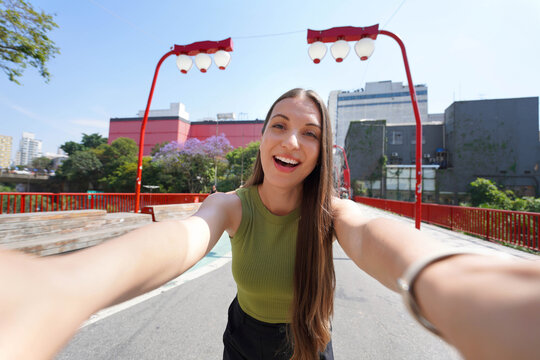 Tourism in Sao Paulo. Beautiful smiling young woman takes self portrait in Liberdade neighborhood of Sao Paulo, Brazil.