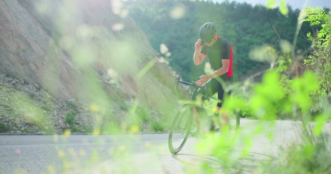 Biker takes a break on a mountain road to enjoy nature and hydrate while cycling