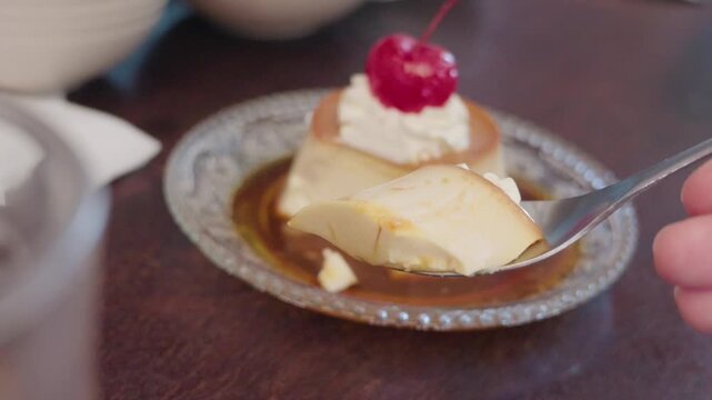 Spoon lifting a bite of caramel custard pudding