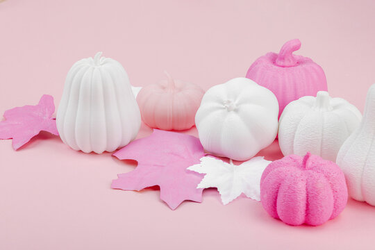 Pink Halloween flat lay with pastel pumpkins and maple leaves. Playful spooky seasonal background