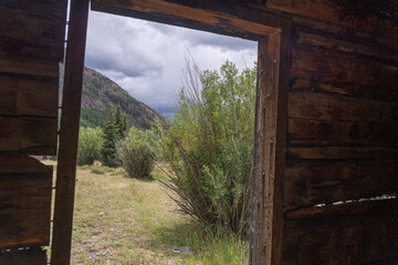 Fototapeta premium View Through Doorway of Abandoned Log Cabin to Mountain Valley