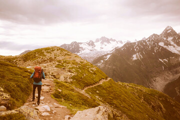 Obraz premium Hiker exploring scenic mountain trail under cloudy sky