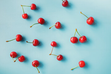 Ripe red cherries scattered on light blue © Diana Vyshniakova