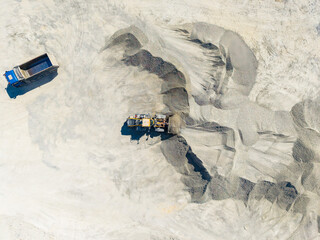 Granite quarry operation shows machinery and dump truck at work in an open area during daylight hours © DSMT