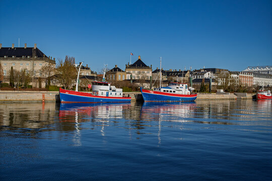 Traditional fishing boats docked in Copenhagen harbor water near Amalienborg Palace on March 27, 2026 in Copenhagen, Denmark 