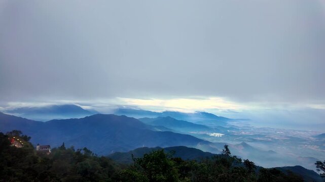 Rising into the Mist: A daytime pan up shot revealing the cloud-covered mountain ranges and valleys of Ba Na Hills, Vietnam