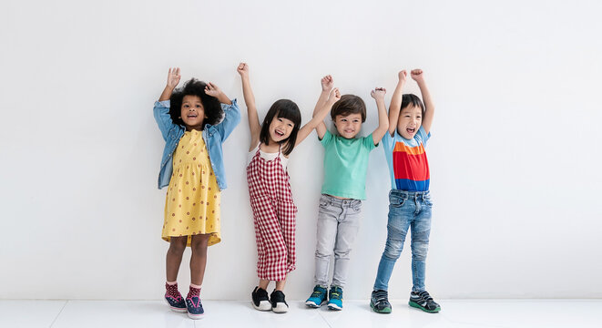 Portrait of diverse children stand in row raise arms jump over white background. Friendship childhood diversity and together. Home school education diversity multicultural community back to school