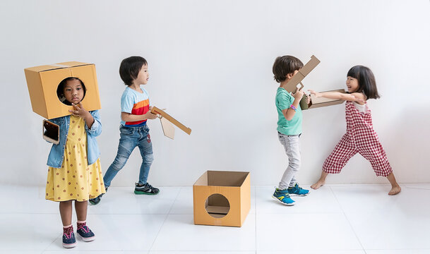 Student in primary school, children creatively playing with cardboard box, pretending, building, and interacting together indoor play space class room. Home school for toddler day care.