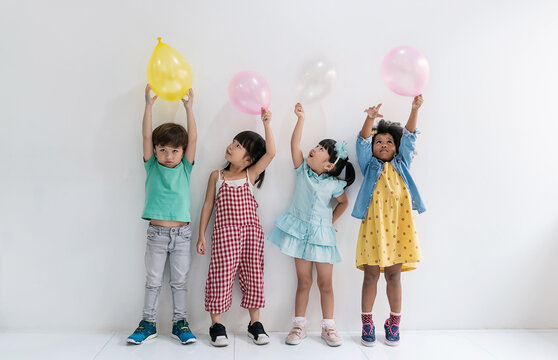 diverse children stand in row holding playing colorful balloons, celebrating childhood fun, friendship indoor activity together. Childhood joy, and special occasions. Christmas vacation holiday vibe.