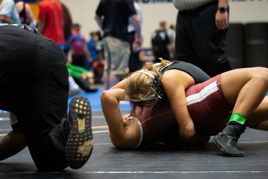 Female wrestlers battling for control during competitive indoor wrestling match