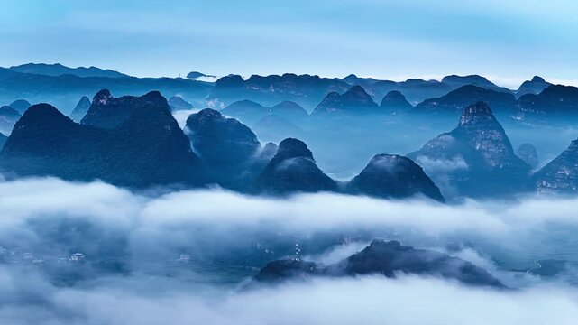 Mist flows over karst peaks during dawn in southwest China, creating a serene mountain landscape scene.