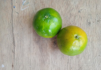 two fresh green oranges on a wooden background © Birul Sinari-Adi