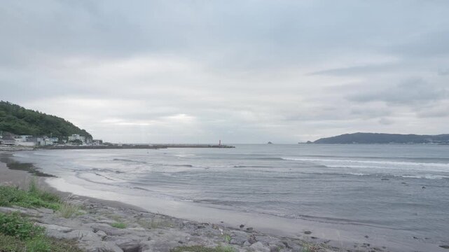 Calm Japanese coastline and small harbor under an overcast sky