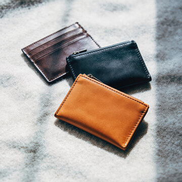 Three small leather wallets flat lay on gray fabric
