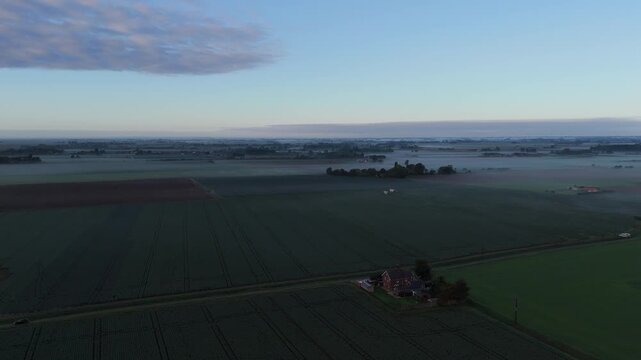 Aerial view of vast green fields under soft dawn sky