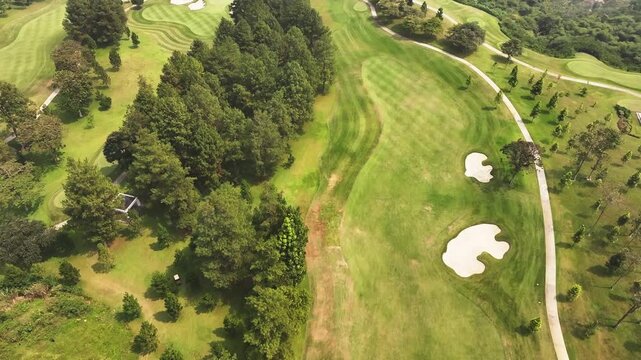Aerial drone view of a lush green golf course and forest landscape