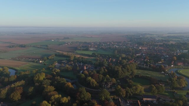 Golden light bathes quiet village nestled among green fields