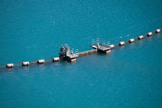 コバルトブルーの奥四万湖に浮かぶ流木止めブイと計測設備 Floating oil/debris boom and monitoring facility on cobalt blue Okushima Lake