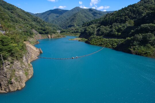 青空と緑豊かな山々に包まれた奥四万湖のコバルトブルーの水面 Okushima Lake surrounded by blue sky and green mountains in Shima Onsen
