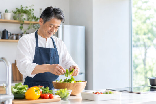 明るいキッチンでサラダを作る日本人男性の健康的な食生活と自炊イメージ
キ