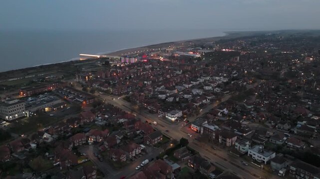 Dusk falls over coastal town with warm lights glowing