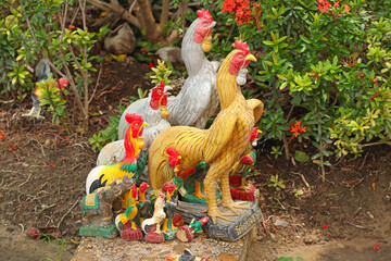 Colorful Rooster and Chicken Statues Placed at Outdoor Shrine © blueringmedia