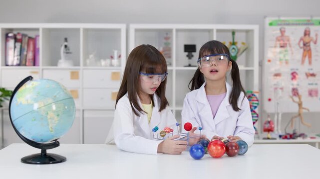 Elementary Students in Lab Coats Presenting Solar System Model in School Laboratory