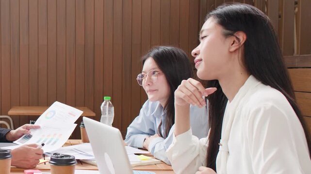 Asian Business Colleagues Discussing Reports and Celebrating Success in Modern Office