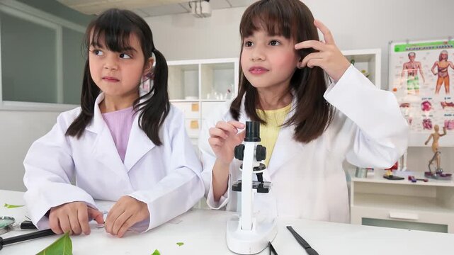 Elementary School Girls Using Microscope in Science Laboratory