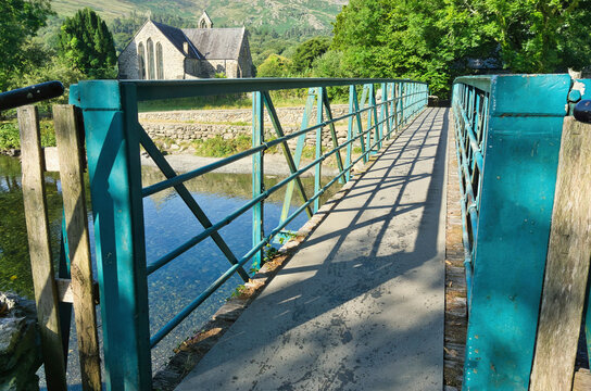 Footbridge over the River Colwyn leading to the historic St Mary's Church in Beddgelert village, Snowdonia National Park, North Wales.
