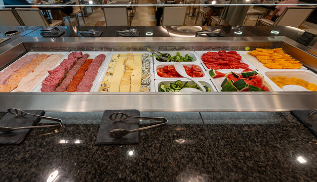 Luxury hotel breakfast buffet with cold cuts, cheese, salad, watermelon, mango, and fresh fruit selection.