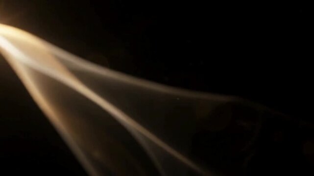 Bright golden lens flare with soft glowing light streaks on dark background