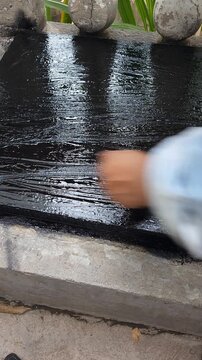 Applying Black Waterproof Paint Brushstrokes On Cistern Base