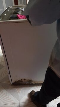 Person Applying Masking Tape To Stove Edges For Restoration